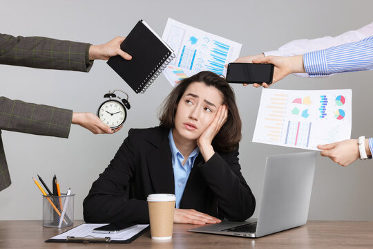 A stressed woman in business attire sits at a desk with a laptop and coffee, while multiple hands surround her holding charts, a notebook, a phone, and an alarm clock, overwhelming her with tasks.