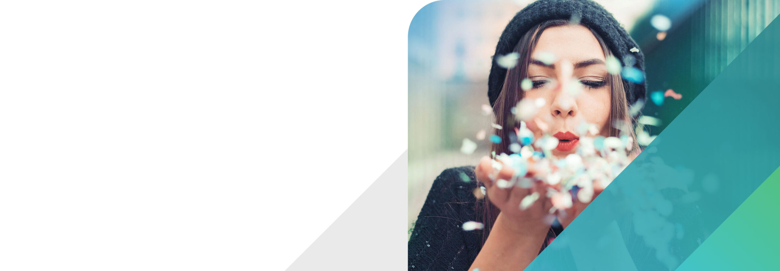 A person wearing a black beanie blows colorful confetti from their hands. The background is blurred, and the scene is partially overlaid with a semi-transparent teal geometric shape on the right.