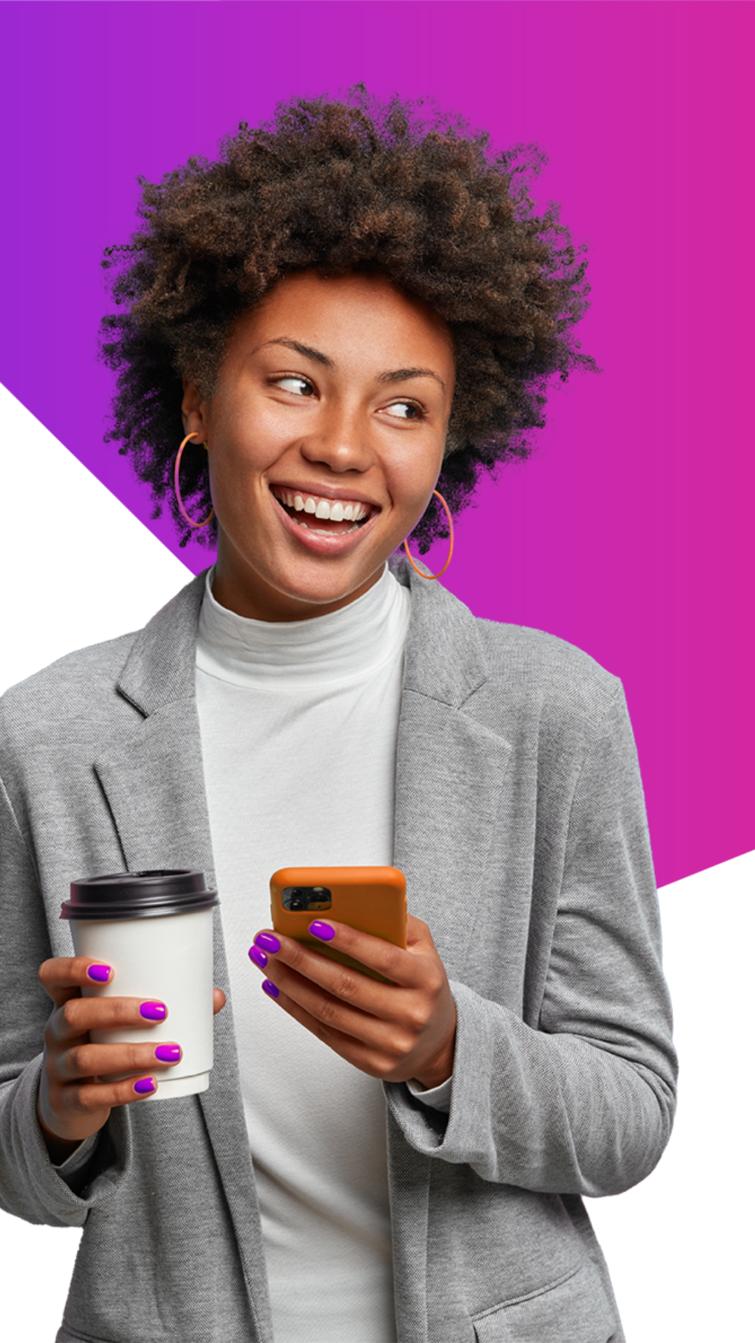 Smiling woman with curly hair holds a coffee cup and a phone, wearing a gray blazer and white turtleneck, standing in front of a vibrant pink and white geometric background.