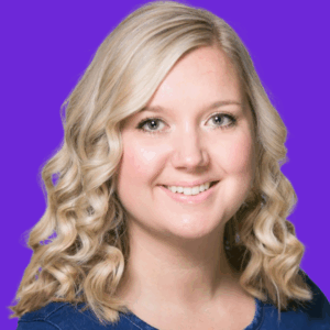 Smiling woman with wavy blonde hair and light skin, wearing a blue top, posing in front of a solid purple background.