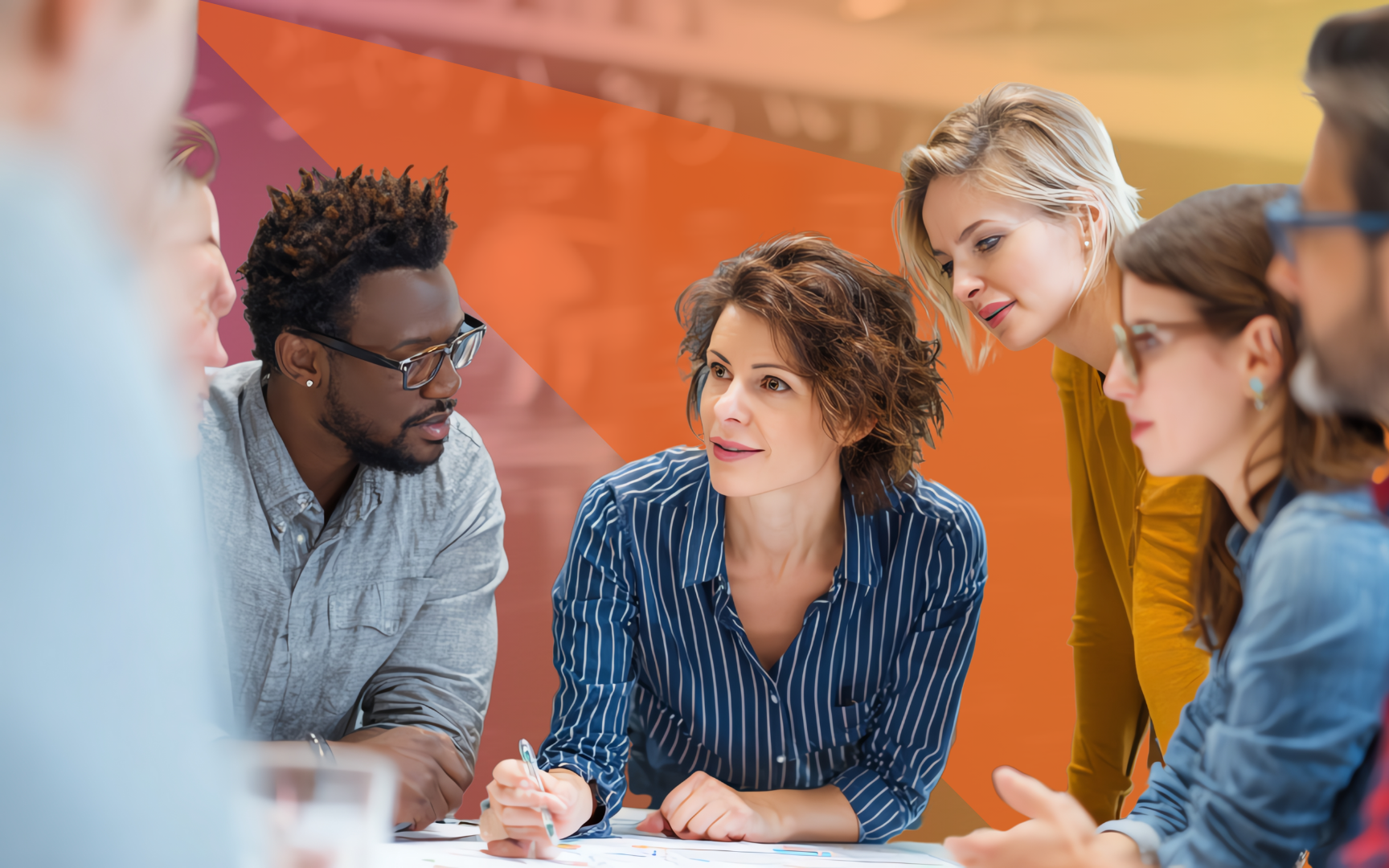 A diverse group of people gathered around a table in a bright, modern office, collaborating and discussing documents, with one woman in a striped shirt leading the conversation.