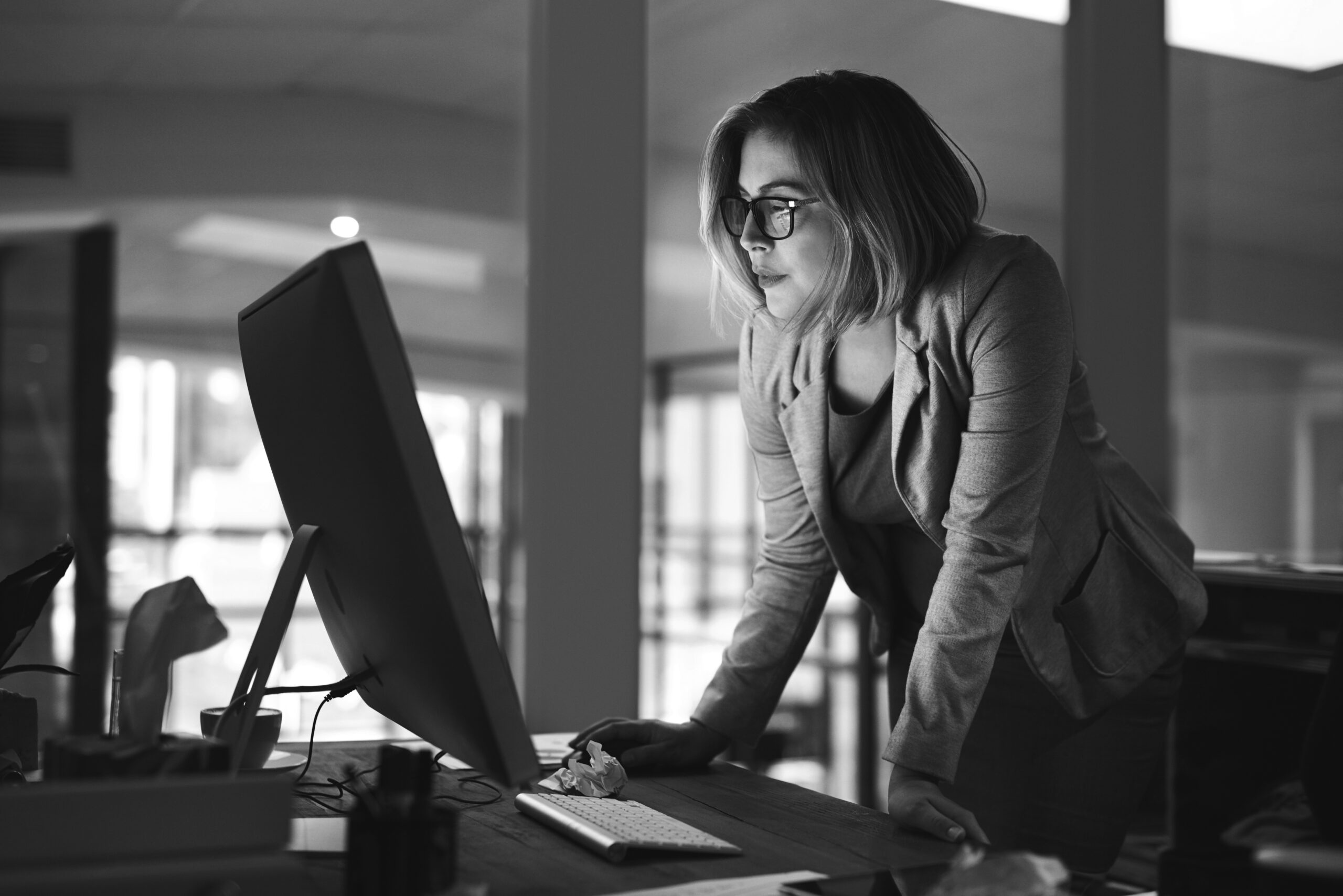 Photograph of executive standing at desk with PC and screwed up paper, representing recognition in the workplace is evolving