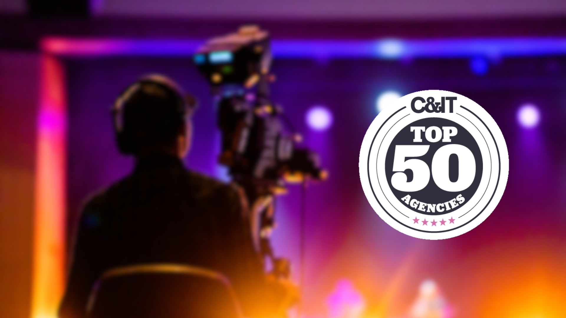 A camera operator films on a brightly lit stage with purple and orange lights. The image features a circular C&IT Top 50 Agencies badge prominently in the foreground.