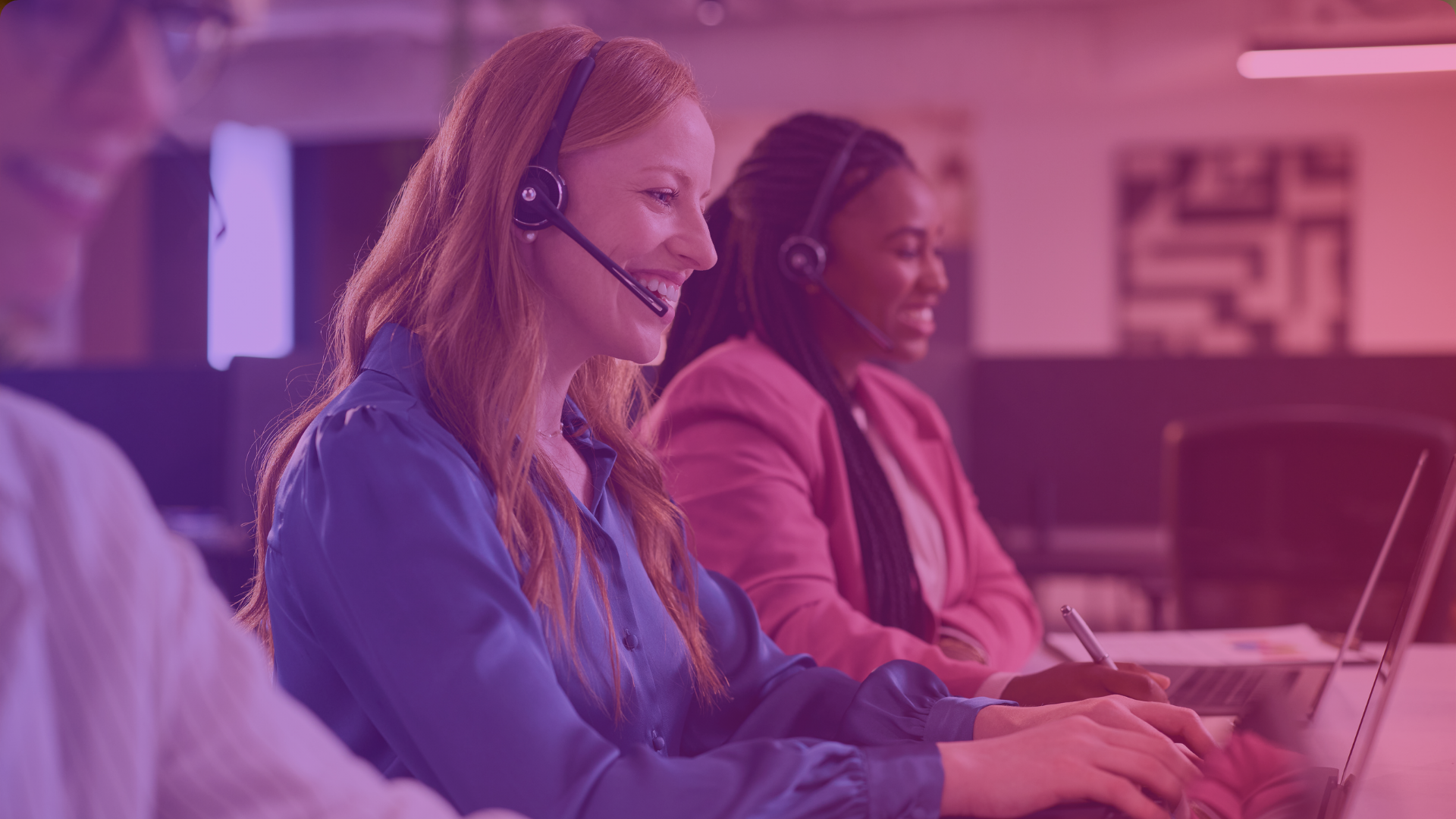 Three people wearing headsets sit at desks, smiling and working on laptops in a modern office environment. The image has a pink and purple color overlay.
