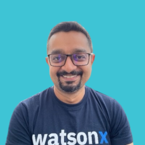 A man wearing glasses and a navy blue shirt with the word watsonx on the front.