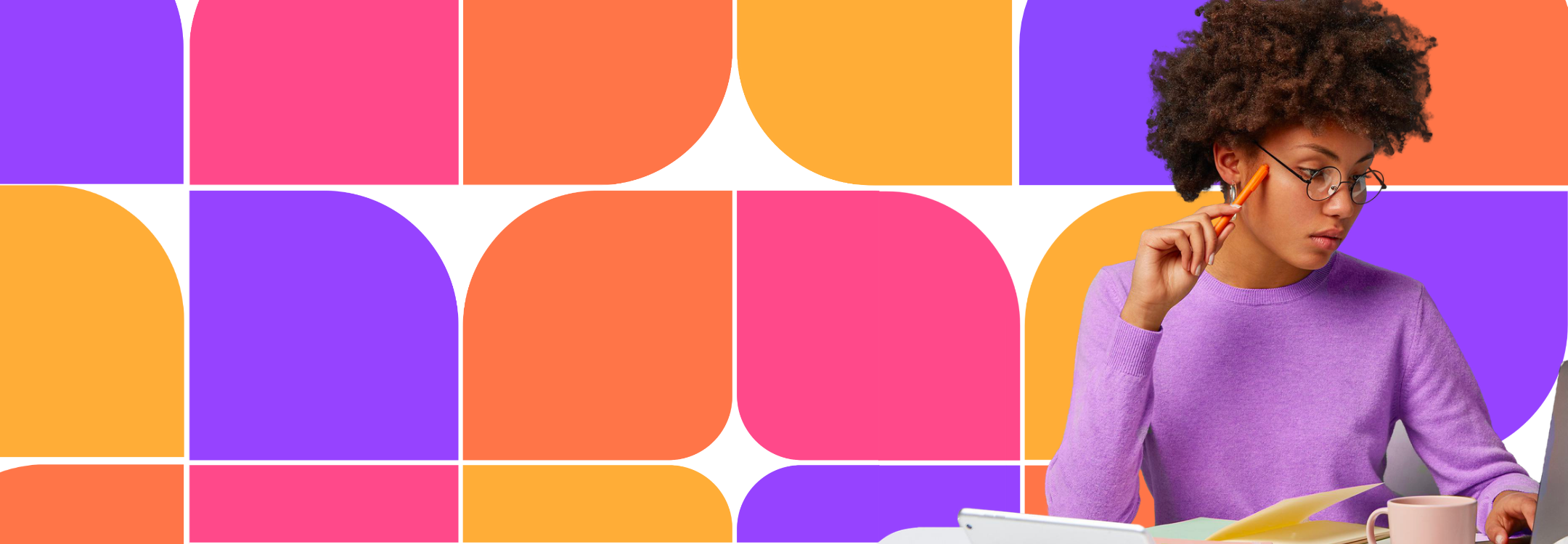 A young person with curly hair and glasses holds a pen while looking down at a laptop and documents against a background of colourful geometric shapes.