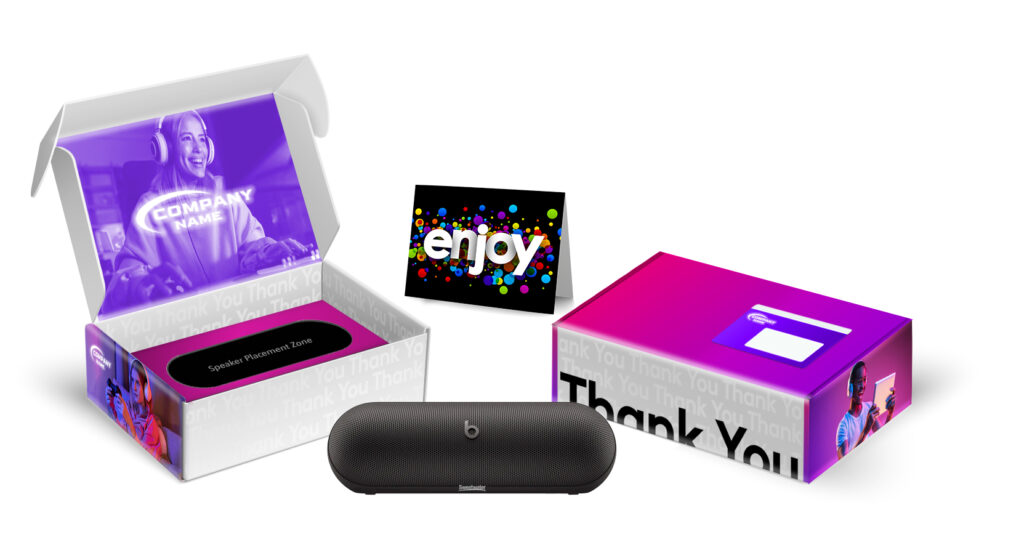 A colorful gift box with “Thank You” text, an open lid showing a card reading “enjoy,” and a black Beats speaker inside. The box features a gamer illustration and customizable company branding.