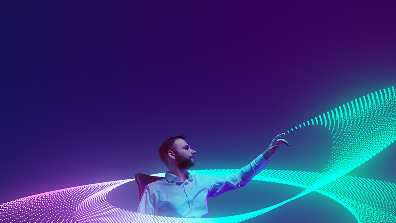 A man in a white shirt sits and reaches out with one hand towards swirling, glowing neon light trails in blue and purple on a dark background.