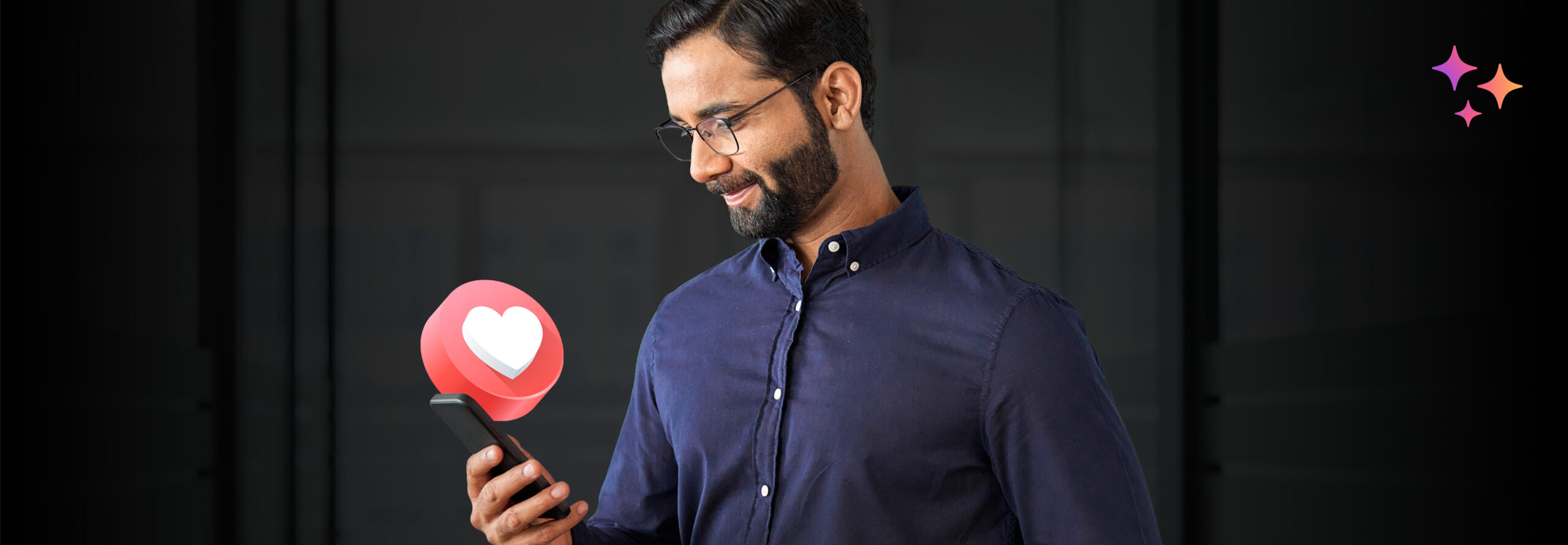 A man wearing glasses and a blue shirt smiles while looking at his phone, with a 3D heart notification icon appearing next to the device. A few colorful star icons are in the top right corner against a dark background.