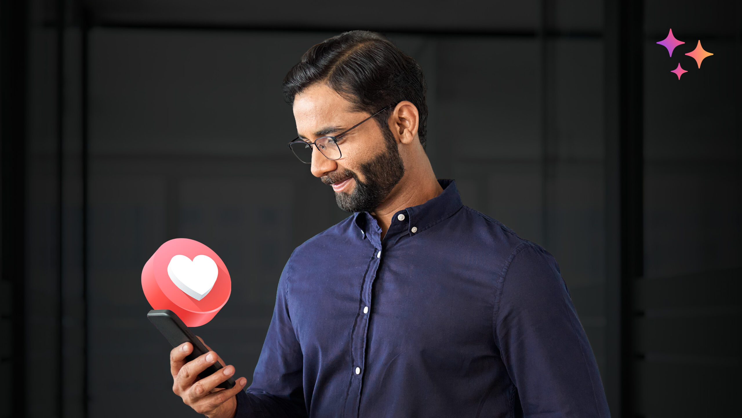 A smiling man with glasses looks at his smartphone, which displays a floating heart icon. He is wearing a navy blue shirt and standing against a dark background with colorful star icons in the top right corner.
