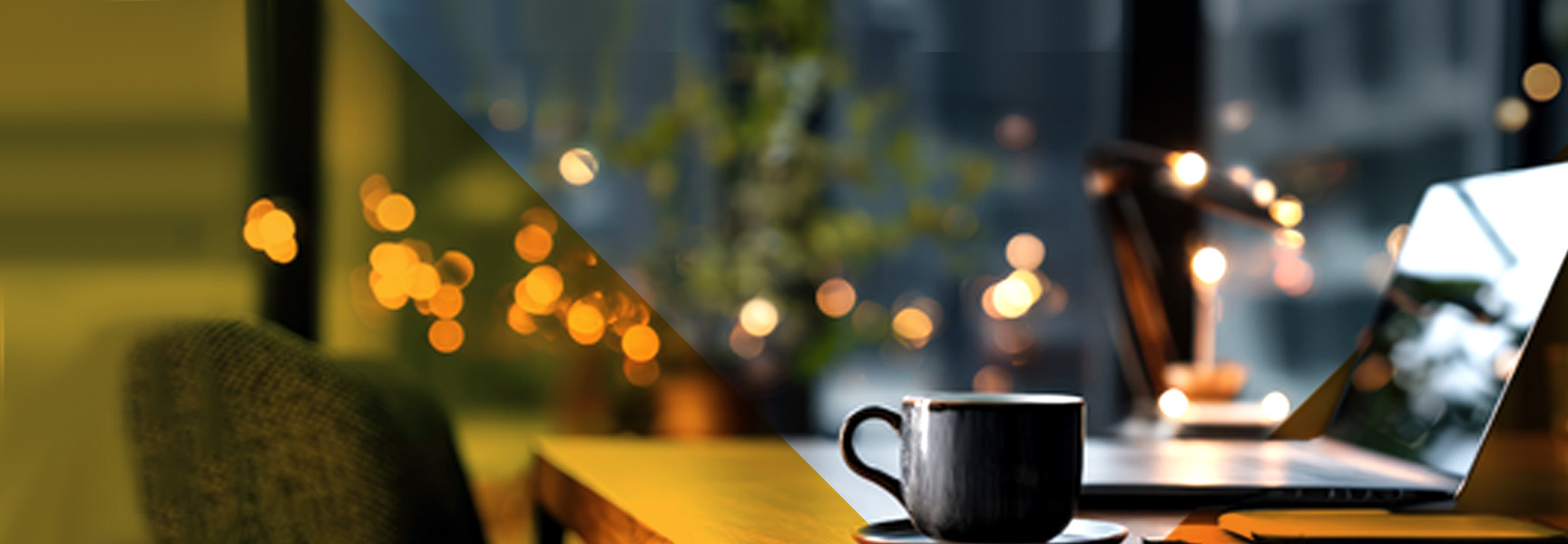 A black coffee cup sits on a wooden table next to a laptop in a cozy, warmly lit indoor setting with blurred lights and greenery in the background.