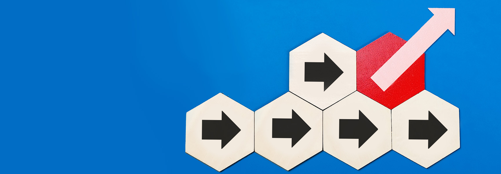 Five hexagonal tiles with black right-facing arrows sit on a blue background; the top right tile is red with a pink arrow pointing upward right, indicating growth or progress.