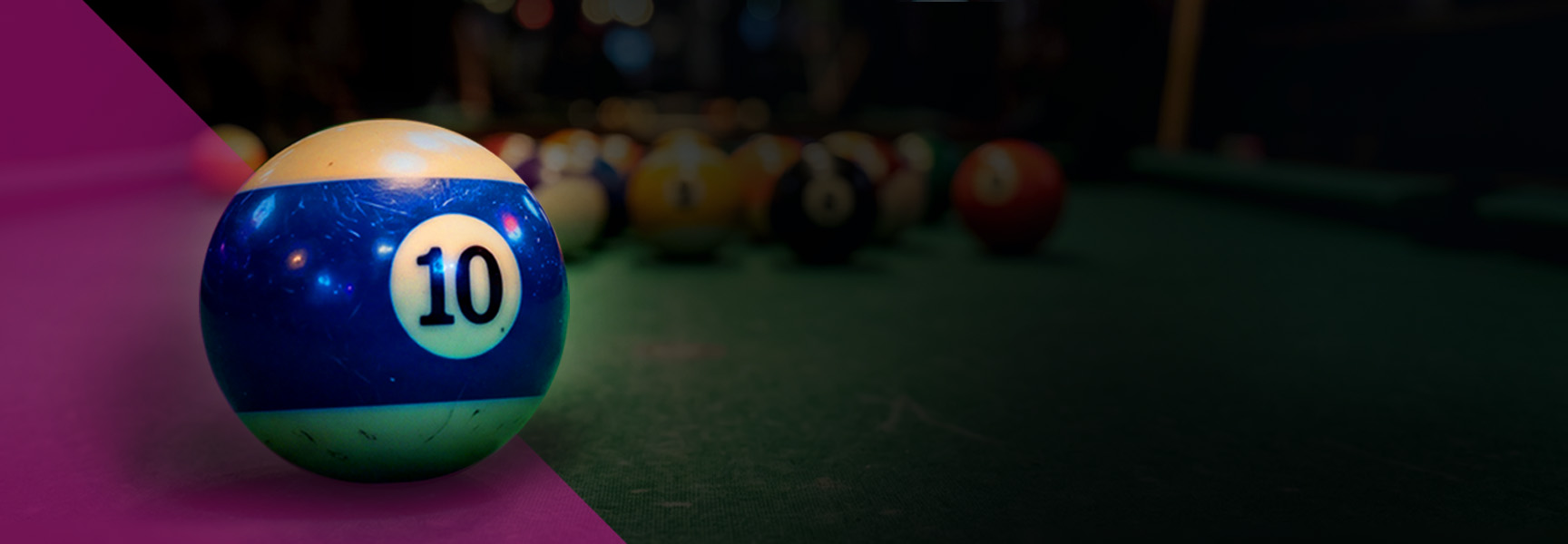 A blue and white number 10 billiard ball sits in the foreground of a pool table with other out-of-focus balls in the background.